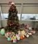 Christmas tree surrounded by a pile of donated toys and plushies in an office corner.