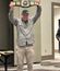 Man holding up a large championship-style belt in a conference room.