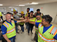 Group of electricians in job trailer with their hands in the middle smiling at the camera. All individuals are in safety vests and PPE gear.