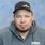 Close-up portrait of a man wearing a black Van Meter cap and gray Interstates hoodie against a light blue background.